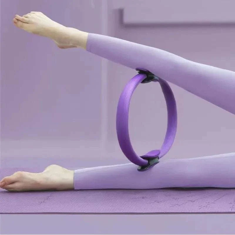 Pilates Ring Magic Circle in purple used for leg workout on yoga mat.